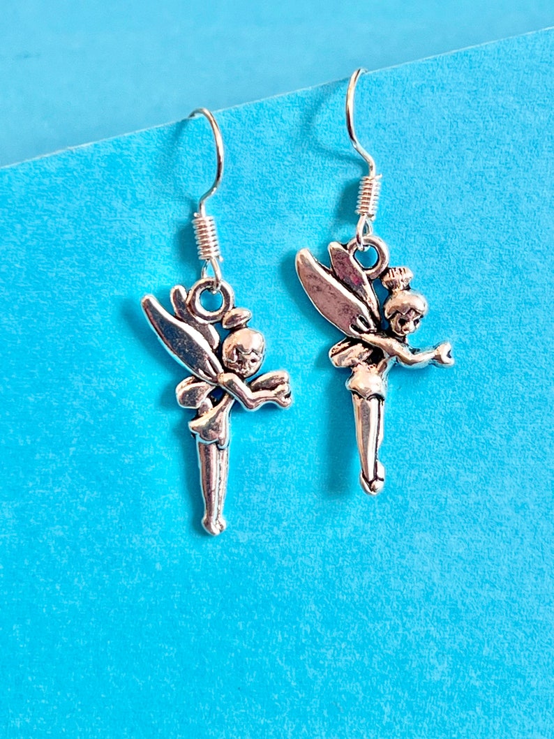 Puede incluir: Un par de pendientes de plata con un dise&ntilde;o de hada. Cada pendiente tiene una delicada figura de hada con alas y un vestido fluido.