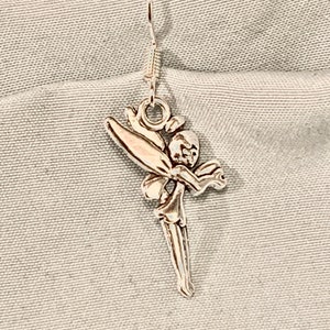 Puede incluir: Pendientes de aro de plata con un dise&ntilde;o de hada. El hada est&aacute; representada con alas, un vestido fluido y una cara delicada.