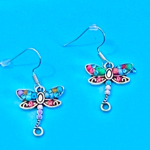 May include: A pair of silver dragonfly earrings with colourful beads. The dragonflies have pink, blue and green accents.