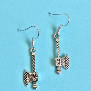 Op de afbeelding: Een paar zilveren bijl oorbellen met een gedetailleerd ontwerp. De oorbellen hebben een eenvoudige haak sluiting.