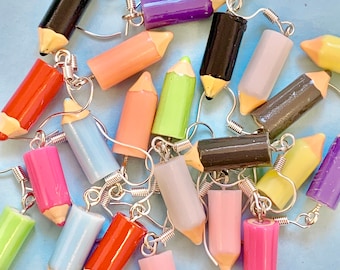 May include: A collection of colorful pencil-shaped earrings. The earrings are made of polymer clay and have a variety of colors, including red, blue, green, yellow, pink, purple, and black. The earrings are all about 2 inches long and have silver hooks.
