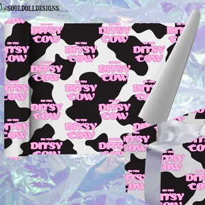 Peut inclure: Papier cadeau imprimé vache noir et blanc avec du texte rose qui dit "On You Ditsy Cow". Le papier cadeau est enveloppé autour d'une petite boîte cadeau avec un ruban blanc.