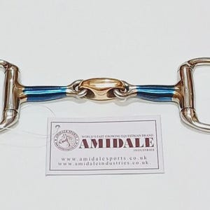 May include: A silver-coloured D-ring horse bit featuring a central gold-toned lozenge link and blue-coated metal bars. A white rectangular tag is attached, displaying the text AMIDALE, the brand logo, and the website addresses amidalesports.co.uk and amidaleindustries.co.uk.