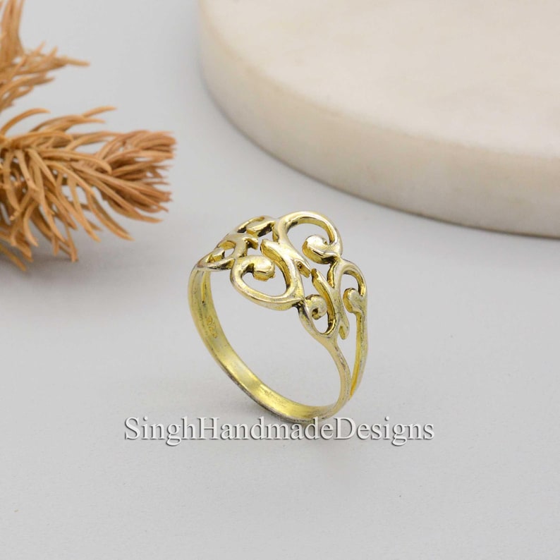 May include: Gold filigree ring with a delicate, intricate design. The ring is made of metal and has a smooth, polished finish.
