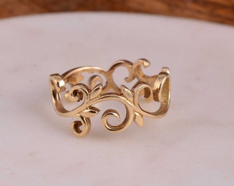 May include: A gold-colored ring with an openwork design featuring swirling vines and leaves. The ring has a delicate, nature-inspired aesthetic, with intricate details and a polished finish. The ring is a size 7.