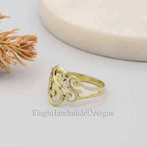 May include: A gold filigree ring with a delicate, intricate design. The ring is made of brass and has a smooth, polished finish.