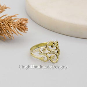 May include: A gold-toned ring with a delicate, intricate design. The ring is made of metal and has a filigree pattern.