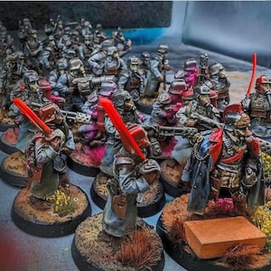 May include: Miniature figurines of a military unit, painted in shades of gray, red, and brown. The figures are posed with weapons and gear, including red lightsaber-like blades. The bases are detailed with miniature terrain.
