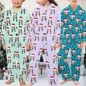K&ouml;nnte beinhalten: Drei Personen tragen passende Pyjamas mit einem Weihnachtsmotiv. Die Pyjamas sind lila, blau und gr&uuml;n mit einem wei&szlig;en Schneeflockenmuster. Jedes Pyjama-Set zeigt ein anderes Gesicht auf dem Stoff.