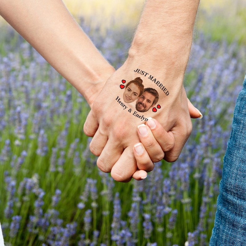 Pu&ograve; includere: Le mani di una coppia con un tatuaggio temporaneo che dice "Just Married" con i loro volti all'interno di un cuore e il testo "Henry & Enelyn" sotto. Il tatuaggio &egrave; sulla mano di un uomo e la coppia si tiene per mano davanti a un campo di lavanda.