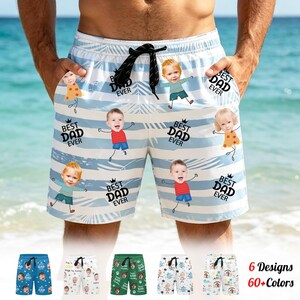 May include: Light blue and white striped swim trunks with cartoon baby faces and the text "BEST DAD EVER." The trunks have a black drawstring and pockets. Additional designs and colors are shown below the main image.