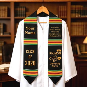 May include: Black graduation stole with gold lettering and a colorful stripe design. The stole has the text "Your Name", "Class of 2026", and "RN, MSN". It also includes the quote "I can do all things through Christ who strengthens me. -Philippians 4:13".
