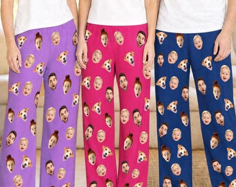 Pode incluir: Três calças de pijama em roxo, rosa e azul, cada uma com um padrão repetitivo de vários rostos humanos e de cães impressos no tecido. Cada calça é combinada com uma t-shirt branca lisa na parte superior do corpo.