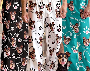 Pode incluir: Três calças de pijama em preto, branco e azul-petróleo, cada uma com um padrão repetitivo do rosto de um cão, o nome Cooper, pegadas e contornos de corações. Um cão pequeno com pelo preto, castanho e branco está sentado em primeiro plano.