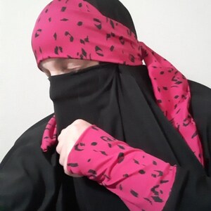 Puede incluir: Un niqab negro con detalles de estampado de leopardo rosa. El niqab incluye una diadema a juego, pu&ntilde;os y una larga bufanda.