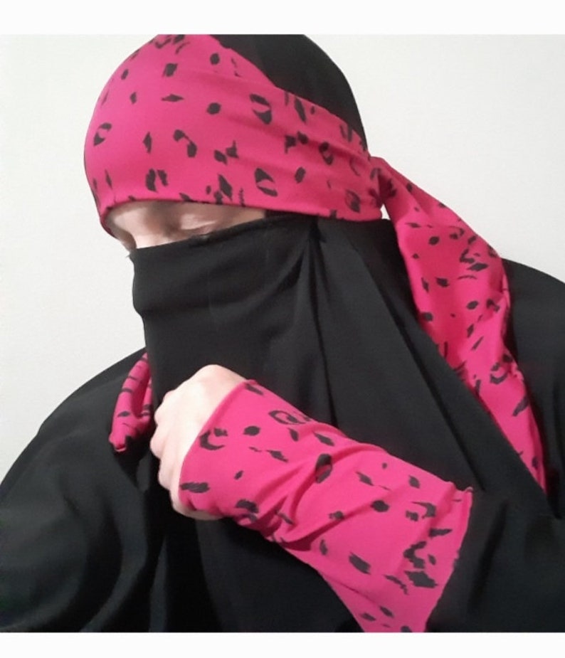 Puede incluir: Un niqab negro con detalles de estampado de leopardo rosa. El niqab incluye una diadema a juego, pu&ntilde;os y una larga bufanda.