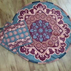 May include: Two teal and pink patterned pot holders with a larger teal and pink patterned round rug with a mandala design.