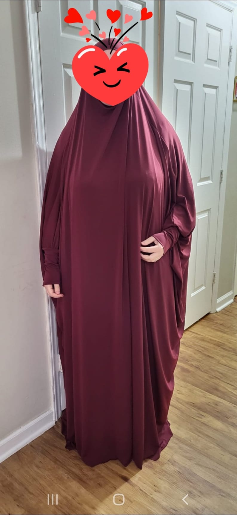 Puede incluir: Una prenda de vestir de color burdeos, de manga larga, holgada y con cuello alto. La prenda est&aacute; hecha de una tela suave y fluida.