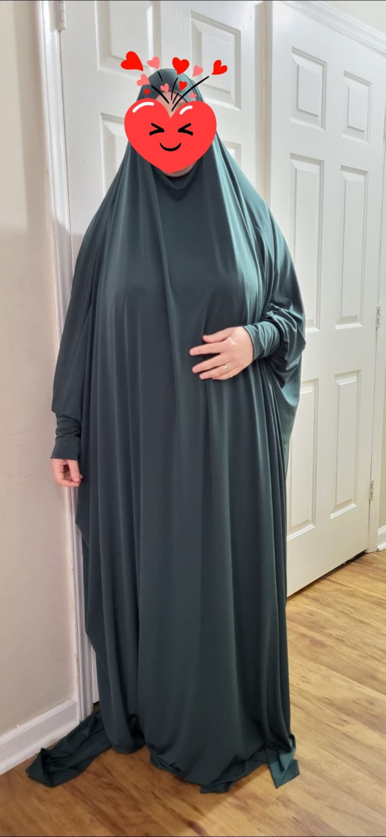 Puede incluir: Una prenda de vestir de color verde oscuro, de manga larga y holgada, con cuello alto. La prenda est&aacute; hecha de un tejido suave y el&aacute;stico y tiene un dise&ntilde;o fluido y drapeado.