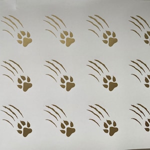 May include: A sheet of white vinyl with 18 gold paw prints and claw marks. Each paw print has four toes and a small heel.