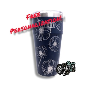 May include: A navy blue Yeti tumbler with a white floral design. The tumbler has a lid and is personalized with the text "FREE PERSONALIZATION!"