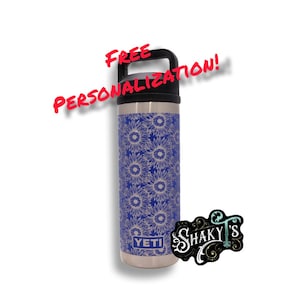 May include: A stainless steel YETI water bottle with a blue sunflower pattern. The bottle has a black handle and the text "FREE PERSONALIZATION!" in red. A "SHAKY'S" logo is also visible.