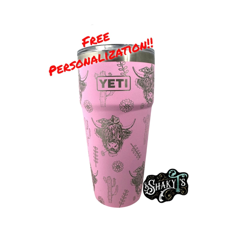 May include: Pink Yeti tumbler with a Highland Cow and cactus design. The tumbler has the word "YETI" printed on it. The text "FREE PERSONALIZATION!!" is written in red above the tumbler. A sticker with the text "SHAKY'S" is in the lower right corner of the image.