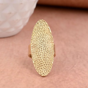 May include: A gold oval-shaped ring with a textured surface.