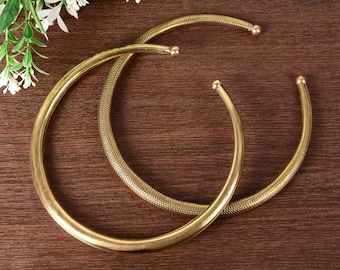 May include: Two gold metal choker necklaces, one with a smooth finish and the other with a textured finish.
