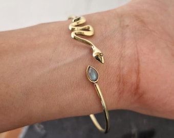 Può includere: Bracciale a forma di serpente dorato con un accento di pietra di luna a forma di lacrima.