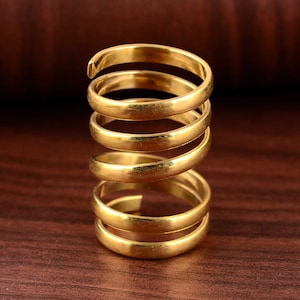 May include: A gold-colored ring made of multiple bands stacked on top of each other, creating a spiral effect.