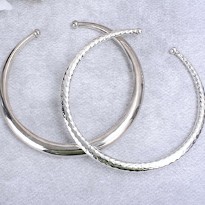 May include: Two silver bangles, one with a smooth finish and the other with a textured finish.