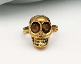 Peut inclure: Une bague en or en forme de crâne avec un design détaillé. Le crâne a un large sourire et de grandes orbites.