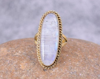 Può includere: Un anello d'oro con una grande pietra di luna ovale incastonata in un design a corda.