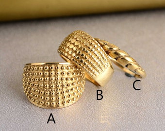 May include: Three gold rings with a textured, dotted surface. The rings are stacked on top of each other. The ring on the bottom is labeled "A", the middle ring is labeled "B", and the top ring is labeled "C".