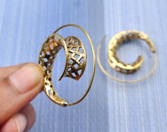 May include: A pair of gold-toned hoop earrings with a spiral design. The earrings are made of metal and have a delicate, intricate pattern.