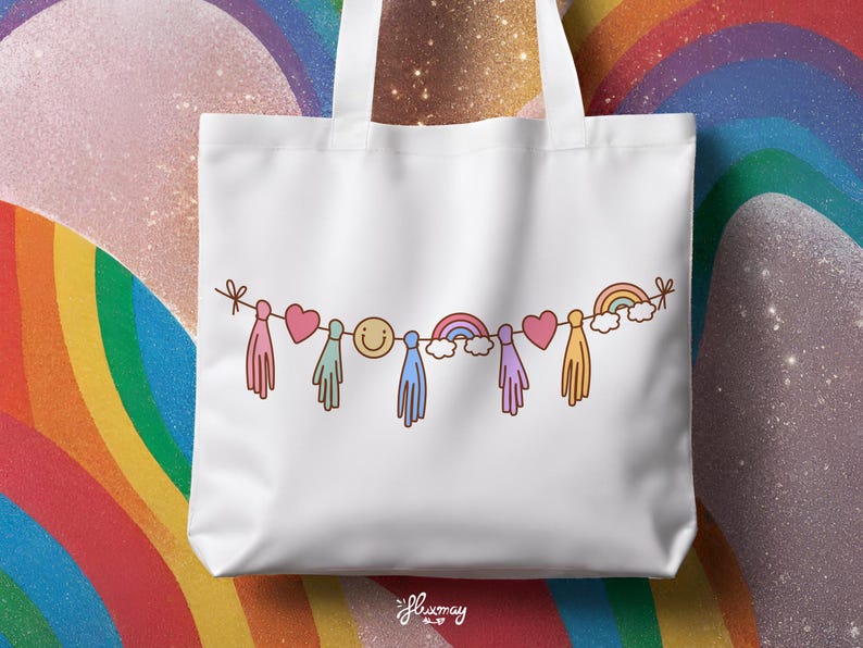 May include: White tote bag with a rainbow garland design. The garland features a smiley face, hearts, rainbows, and tassels.