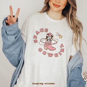 May include: White t-shirt with a pink cowboy boot graphic and the text "Space Cowgirl" in a retro font.