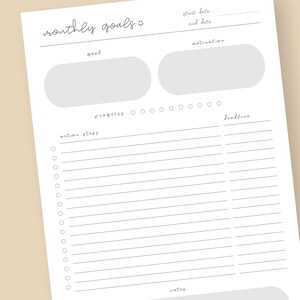 Puede incluir: Un planificador mensual de objetivos blanco, sin fecha, con secciones para objetivos, motivaci&oacute;n, pasos de acci&oacute;n y plazos. El planificador incluye un seguimiento del progreso y espacio para notas. El t&iacute;tulo "objetivos mensuales" est&aacute; escrito a mano.