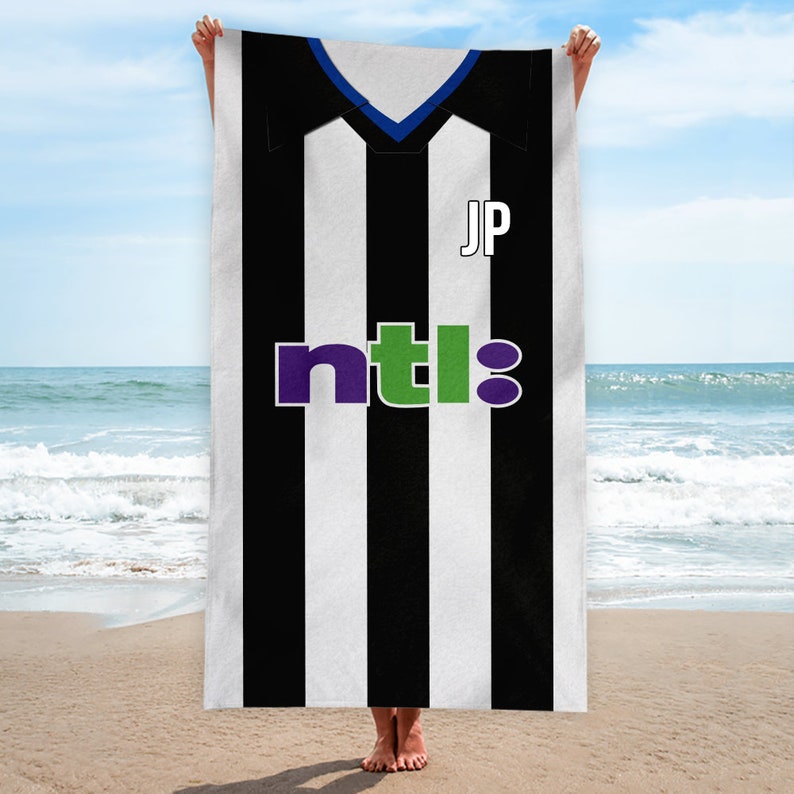 May include: Black and white striped beach towel with a blue collar and the text "ntl" in purple, green, and white. The towel also has the initials "JP" in black.