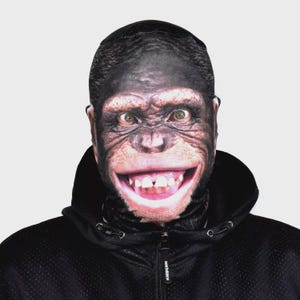 May include: A full-face mask with a realistic chimpanzee face printed on it. The mask features a detailed depiction of a chimpanzee's facial features, including eyes, nose, mouth, and fur. The person is wearing a black hooded jacket.