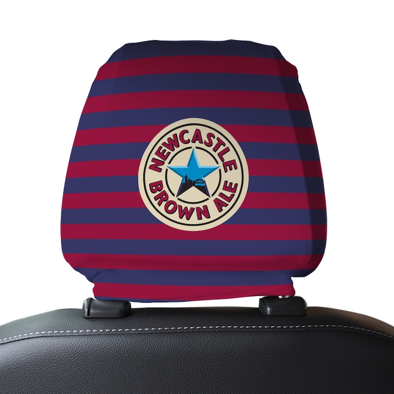 Op de afbeelding: Rode en blauwe gestreepte autostoel hoofdsteunhoes met een wit cirkelvormig logo met de tekst "Newcastle Brown Ale" met een blauwe ster en een skyline van de stad in de cirkel.