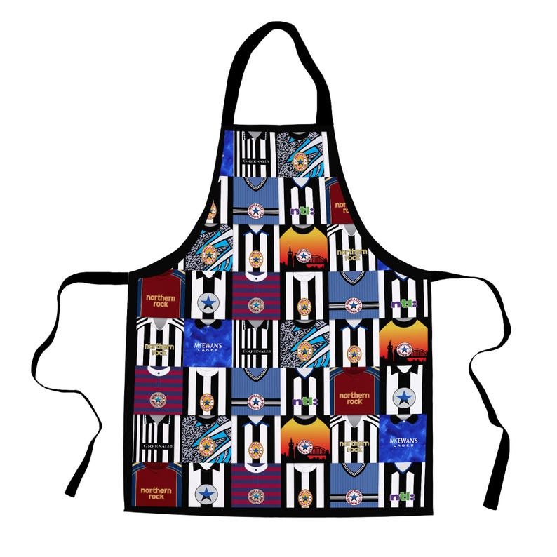 May include: Black apron featuring a collage of Newcastle United football jerseys in various colors and designs. The apron has a black neck strap and ties, and the jerseys include the "Northern Rock" and "MCEWANS LAGER" logos.