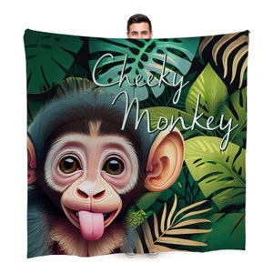 May include: A green, brown and black throw blanket with a cartoon monkey face and the text "Cheeky Monkey" in white cursive.