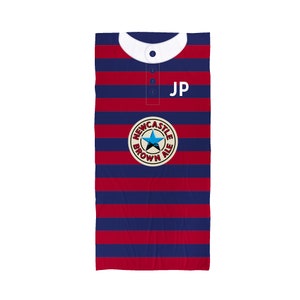 Peut inclure: Un maillot ray&eacute; rouge et bleu avec un col blanc et un logo Newcastle Brown Ale. Le maillot porte les initiales "JP" sur le devant.
