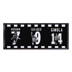 May include: Black and white framed print featuring three soccer players: Keegan, Shearer, and Ginola. Each player is depicted in action with their jersey number prominently displayed. The frame has a black and white checkered border.