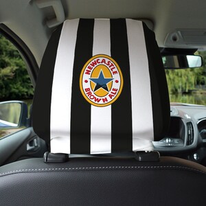 Puede incluir: Reposacabezas de asiento de coche a rayas blancas y negras con un logotipo de Newcastle Brown Ale en el centro. El logotipo es un c&iacute;rculo rojo con una estrella amarilla y las palabras "Newcastle Brown Ale" en blanco.