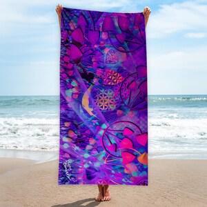 Könnte beinhalten: Ein lebendiges Strandtuch mit einem psychedelischen Design in Lila-, Rosa- und Blautönen. Das Tuch zeigt abstrakte Formen, Herzen und geometrische Muster. Das Tuch wird an einem Sandstrand mit dem Ozean und dem Himmel im Hintergrund gehalten.