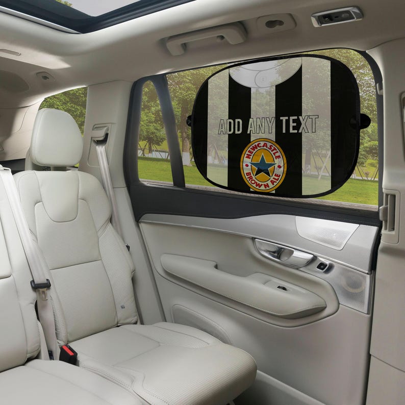 May include: Black and white striped car window sunshade with the text "ADD ANY TEXT" and a Newcastle Brown Ale logo. The sunshade is oval-shaped and attached to the car window.