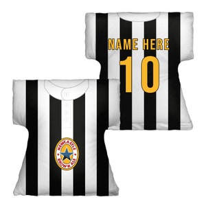 May include: Two black and white striped pillows shaped like a football jersey. One pillow has the text "NAME HERE" and the number "10" in yellow. The other pillow has a Newcastle Brown Ale logo.